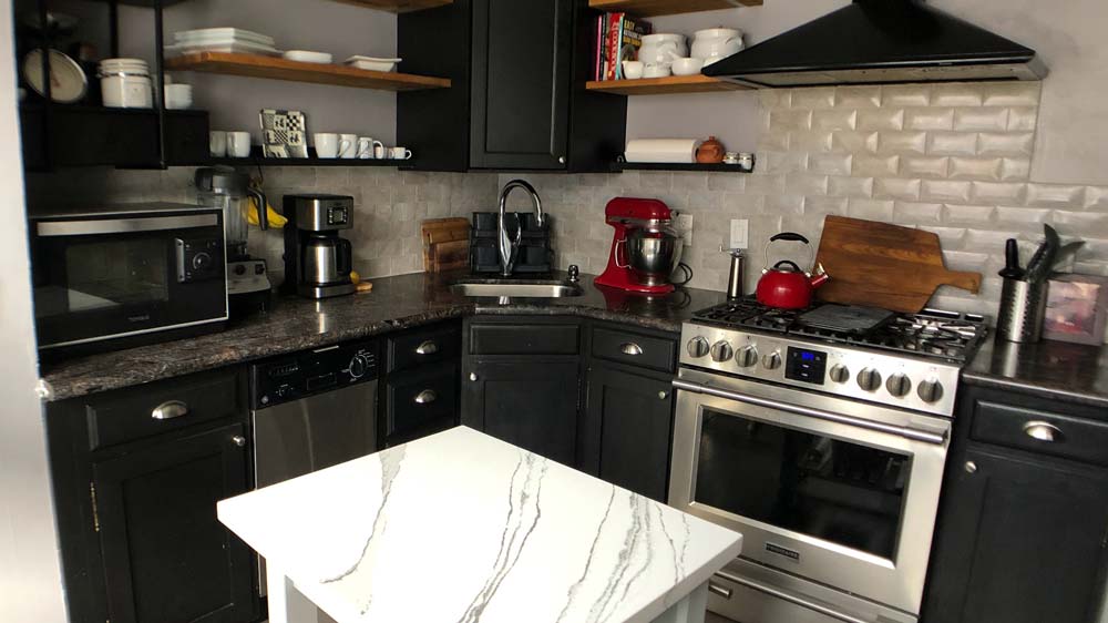 Corner of a kitchen with a stainless steal oven and vent hood