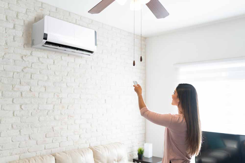 Woman adjusting air conditioning with remote control
